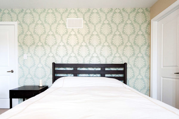 bedroom wallpaper behind the queen size wooden bed.