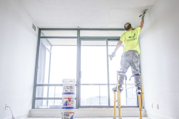 house painters, Professional house painter working on popcorn ceiling removal in condo with large windows using stilts, popcorn ceiling removal, how to remove popcorn ceiling, popcorn ceiling, how to paint popcorn ceiling, painted popcorn ceiling removal, popcorn paint removal