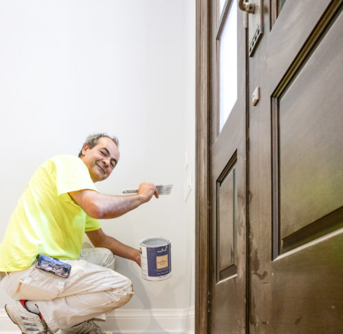 Painter doing interior painting of a light gray wall in Toronto, Ontario, Canada by Home Painters Toronto