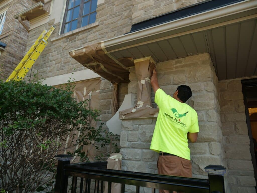 Exterior Painting Brick Staining Light Grey male painter prepping stone house for painting