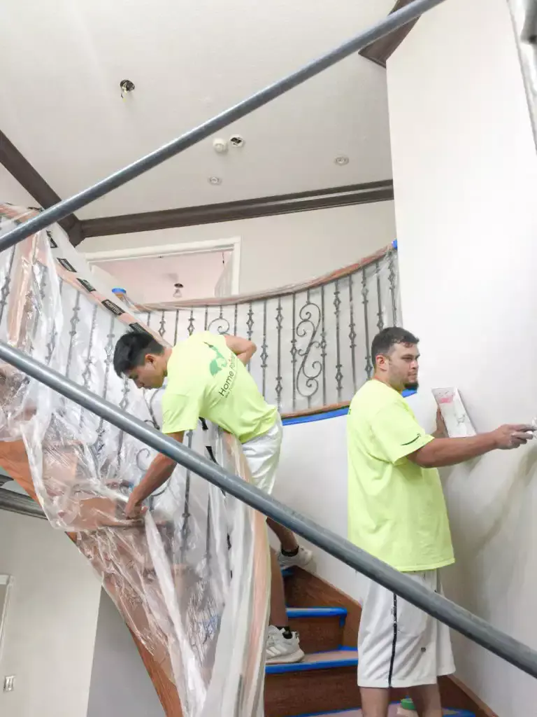 two painters painting interior house staircase and staining