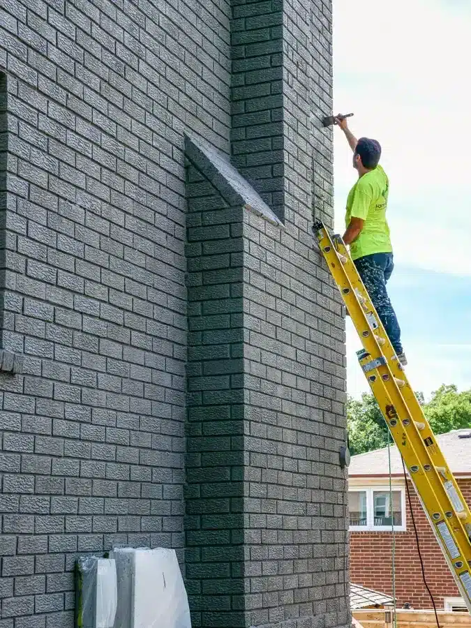 Exterior Brick Staining Painter Working On Ladder
