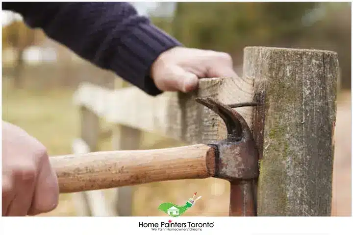 Painter-removing-rotted-wood-fence