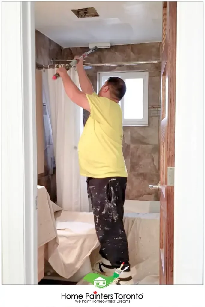 painter painting the ceiling using roller brush